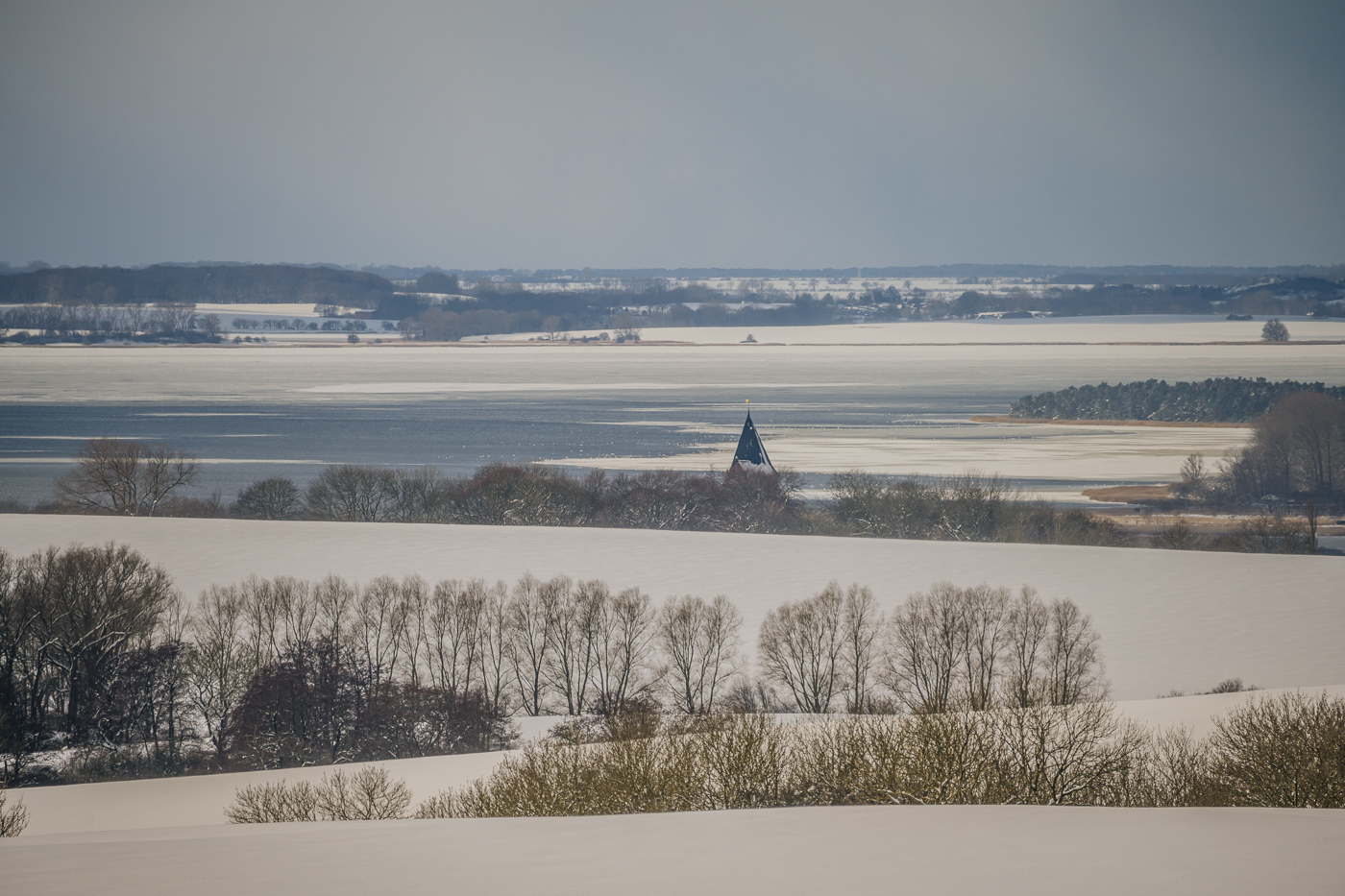 Die Kirchturmspitze von Bobbin und der vereiste Große Jasmunder Bodden